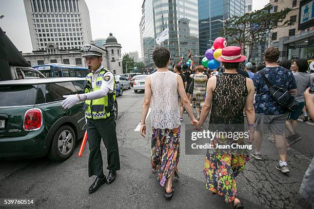 Kim Seung-Hwan and his partner, Kim Jho Gwang-Soo , walk past a policeman during the Queer Festival on June 11, 2016 in Seoul, South Korea. While the...