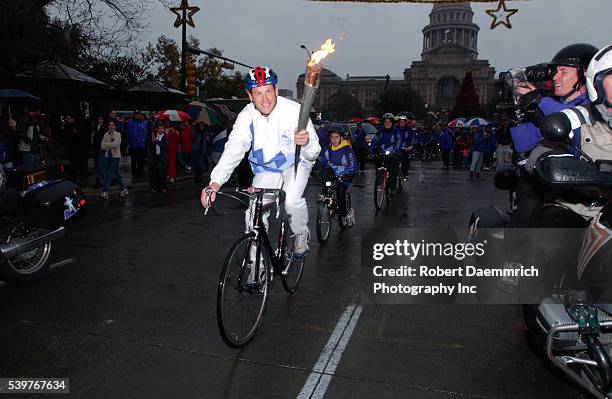 Tour de France winner Lance Armstrong carries the Olympic Torch on his bicycle, down Congress Avenue in Austin, during the Salt Lake City Olympics...