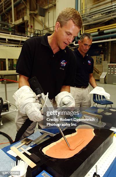 Astronaut Scott Parazynski, who will possibly fly on upcoming STS-118, demonstrates how tile filler material will be used to fill holes in space...