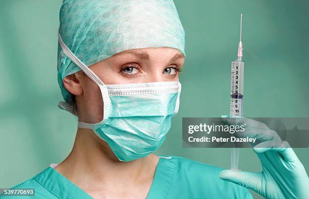 lady surgeon doctor with syringe - surgeon holding needle stock-fotos und bilder