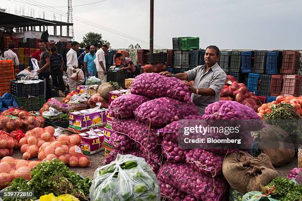 Porter stands next to goods at a wholesale vegetable market in Dharamsala, India, on Thursday, June 9, 2016. Consumer Price Index figures for May are...