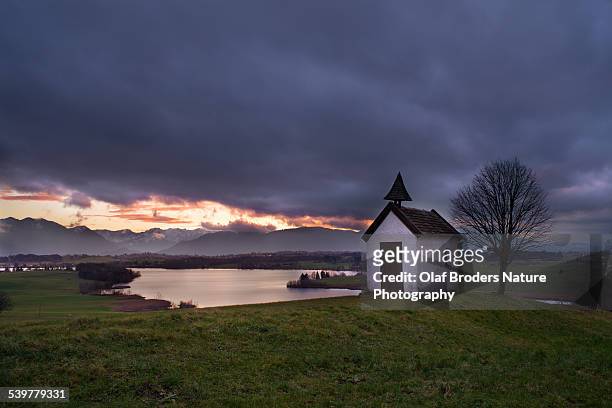 bavarian chapel in front of lake riegsee at sunset - lake riegsee stock pictures, royalty-free photos & images