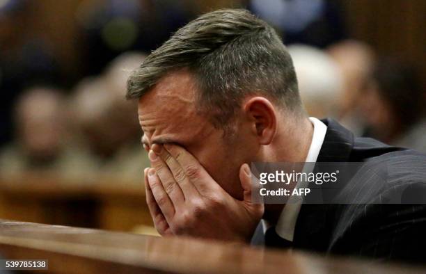 South African Paralympian Oscar Pistorius reacts as he sits in the dock during his sentencing hearing at the Pretoria High Court for murdering his...
