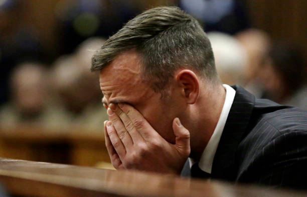 South African Paralympian Oscar Pistorius reacts as he sits in the dock during his sentencing hearing at the Pretoria High Court for murdering his...