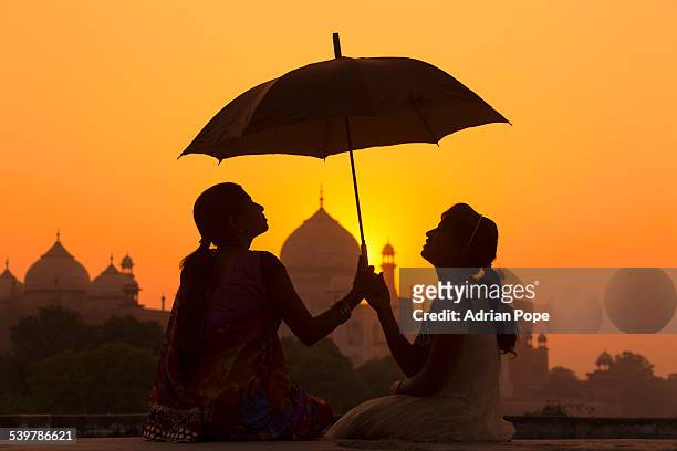 sisters at sunset with taj mahal beyond - アーグラ ストックフォトと画像