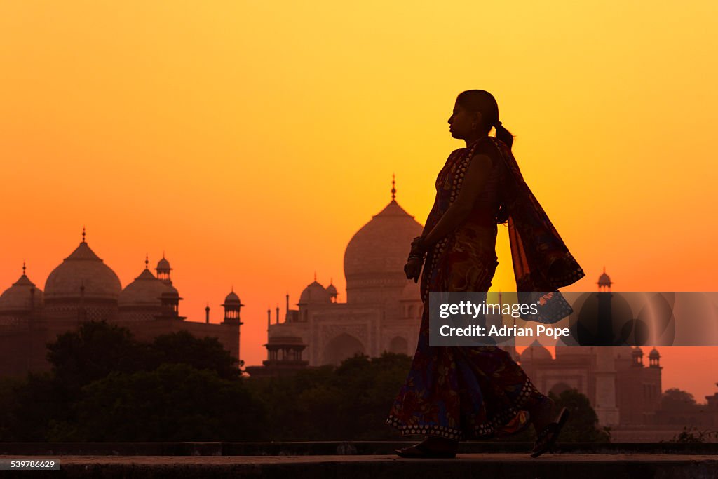 Indian woman walking at sunset near Taj Mahal