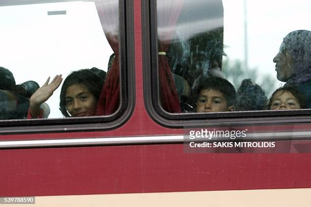 Child waves as migrants on a bus are evacuated from the makeshift camp at the Greek-Macedonian border near the village of Polykastro on 13 June,...