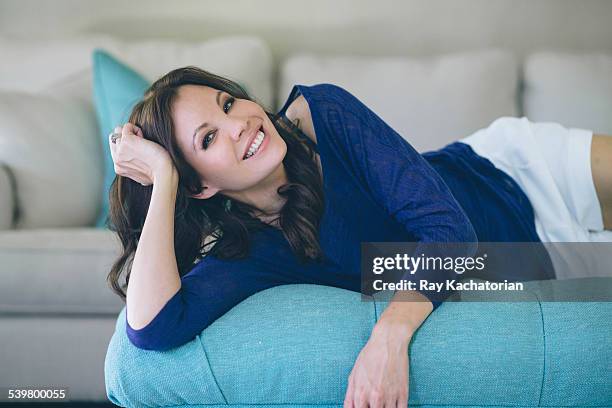 woman laying on couch smiling - one mature woman only stock pictures, royalty-free photos & images