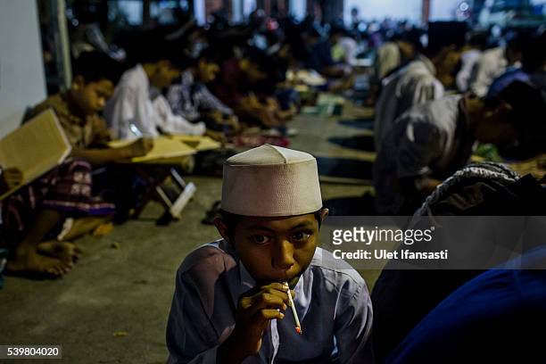 Student smoking as they learn Islamic scriptures at the islamic boarding school Lirboyo during the holy month of Ramadan on June 9, 2016 in Kediri,...