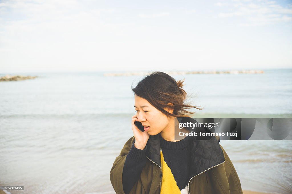 Young woman takes a phone call on the beach