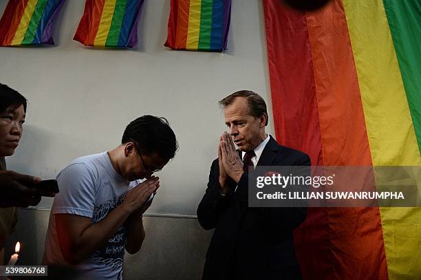 Ambassador to Thailand Glyn T. Davies gestures to members of the LGBT community outside the US Embassy in Bangkok on June 13, 2016 during a vigil for...