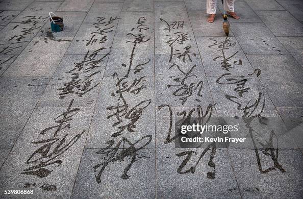 Beijing Writing A Chinese man uses a brush to write calligraphy in water, known as Di ...