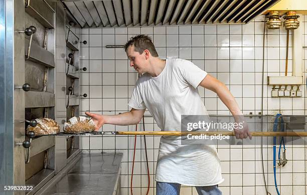 baker taking bread out of oven - french boulangerie stock pictures, royalty-free photos & images