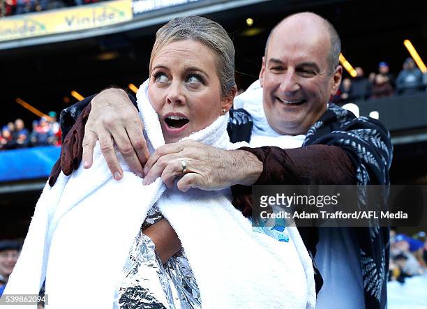 Sam Armytage is handed a towel by David Koch after going down the Freeze MND slide during the Big Freeze 2 during the 2016 AFL Round 12 match between...
