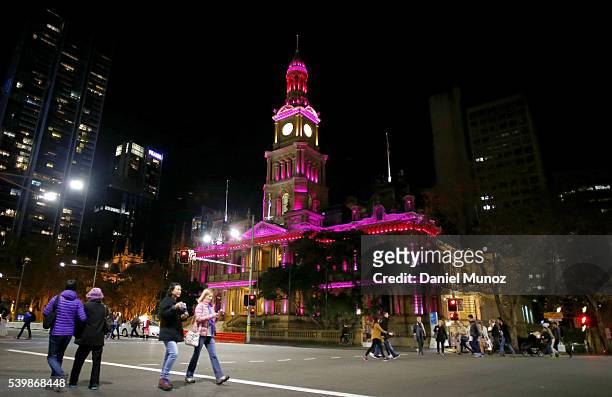Pedestrians walk past Sydney Town Hall which is illuminated pink to remember victims of the Orlando night club massacre on June 13, 2016 in Sydney,...