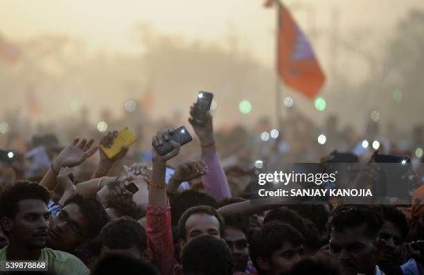 Supporters of India's Bharatiya Janta Party wave their cellular telephones in the air as they listen to Indian Prime Minister Narendra Modi as he...