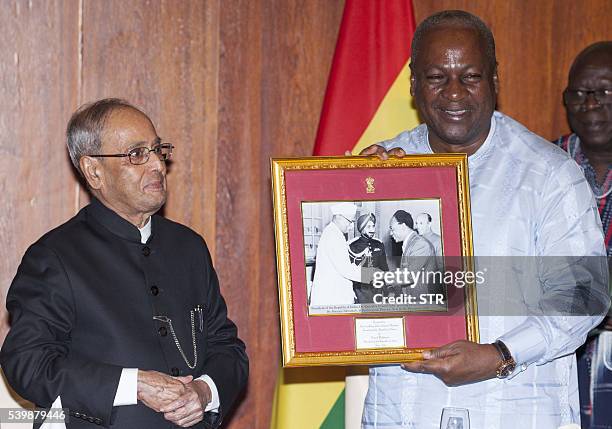 Ghanaian President John Mahama stands by his Indian counterpart Pranab Mukherjee as he holds a framed photography taken on December 1958 showing...