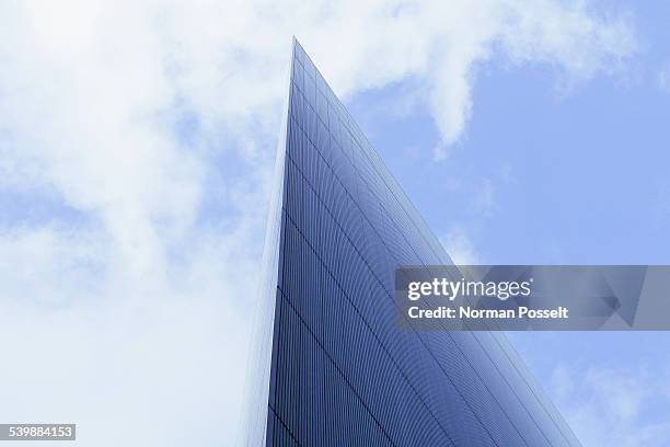 low angle view of modern glass building against cloudy sky - pointy architecture stock pictures, royalty-free photos & images