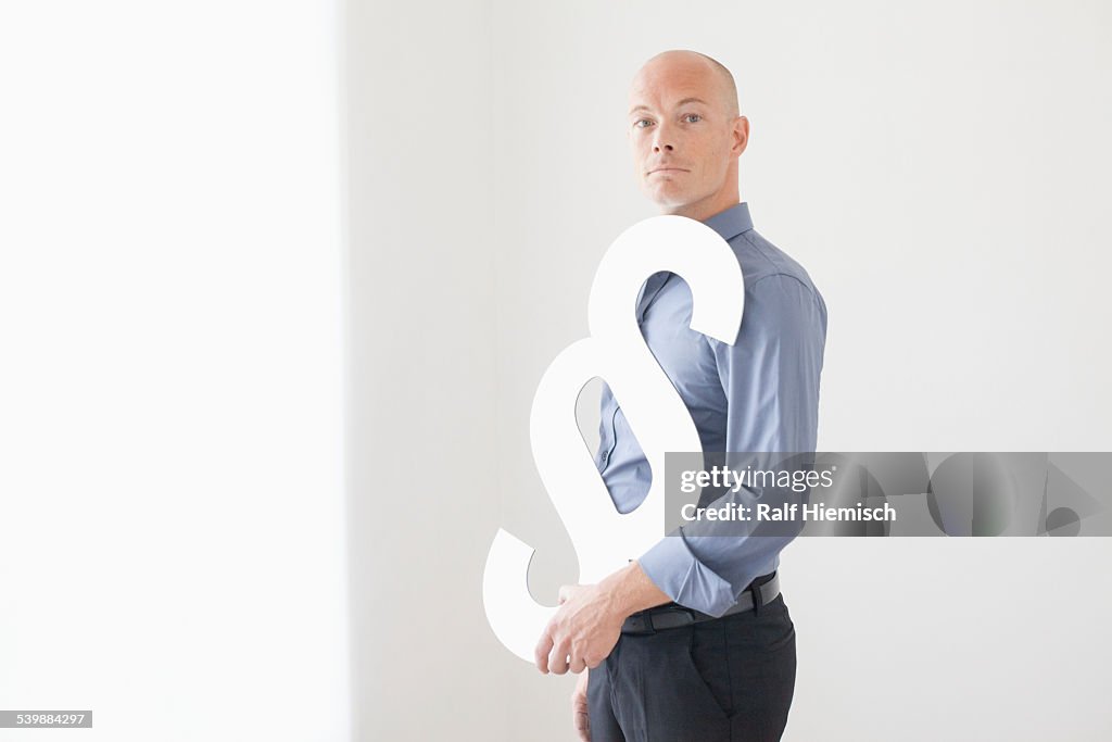 Side view portrait of businessman holding paragraph sign at office