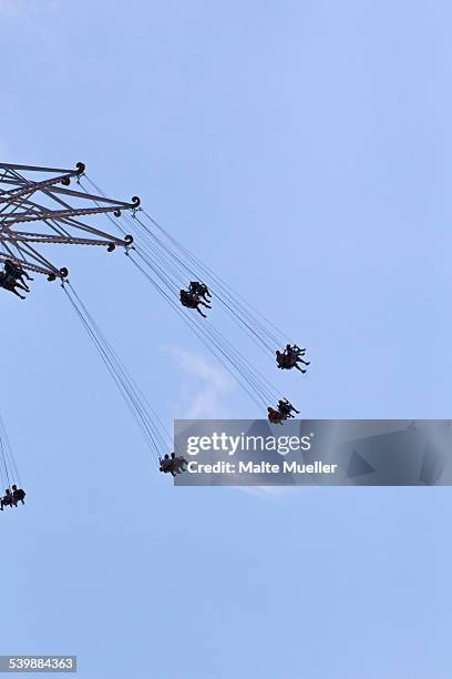 low angle view of people enjoying on chain swing ride against blue sky - zweefmolen stockfoto's en -beelden