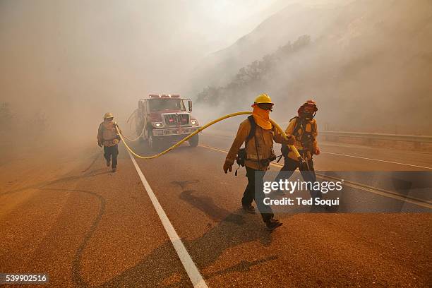 Fire crew walks up Grimes Canyon with a foam truck, putting out spot fires on the sides of the road. 9000 acre Guiberson wildfire burns out of...