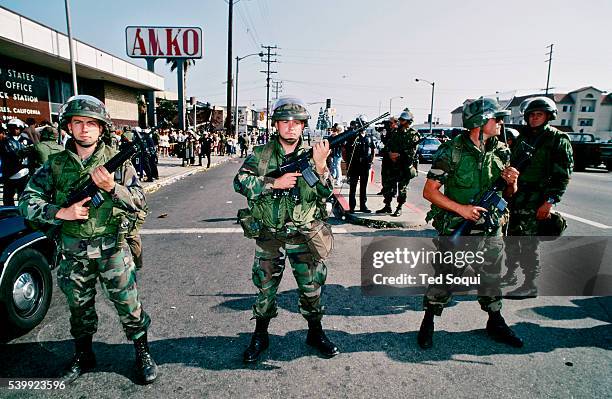 Armed National Guard soldiers hold a line in front of a post office in South Central L.A. Many South Central residents are expecting their monthly...