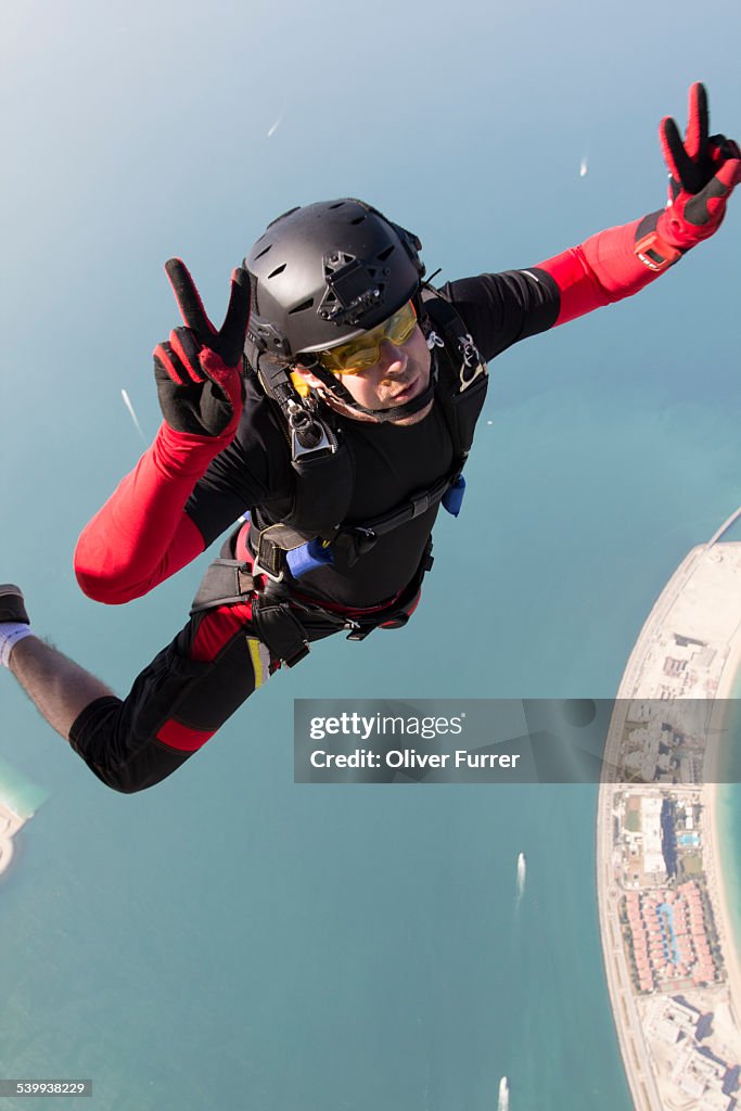 Skydiver over Dubai with peace sign