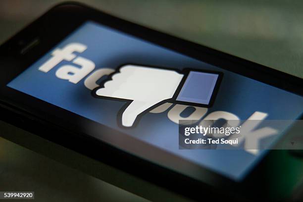 Facebook thumbs-down hand on a iPhone. Facebook is a social media company owned by Mark Zuckerberg.