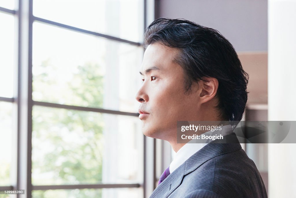 Sérieux homme d'affaires japonais recherche par la fenêtre dans la Contemplation