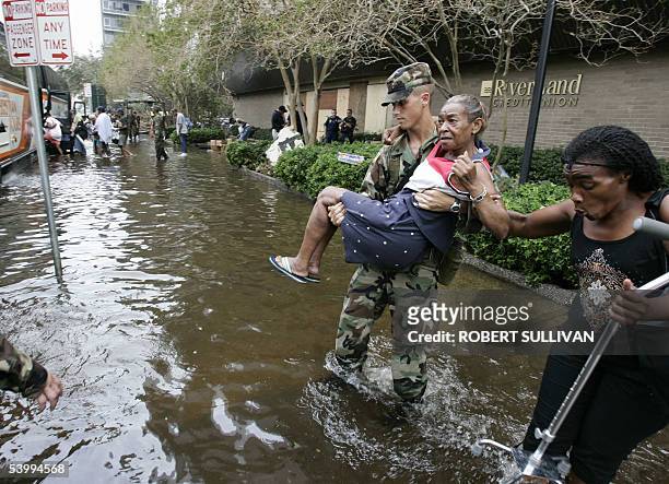 New Orleans, UNITED STATES: An elderly woman is carried by a Louisiana National Guardsman after gunshots were heard as people were evacuated from the...