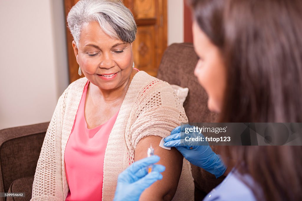 Home healthcare nurse giving injection to senior adult woman.