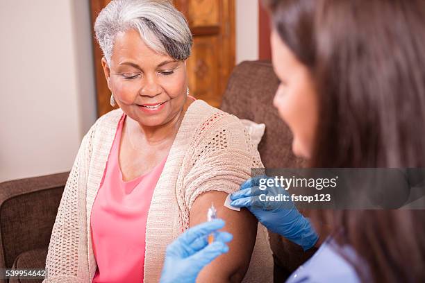 home healthcare nurse giving injection to senior adult woman. - flu vaccine stock pictures, royalty-free photos & images