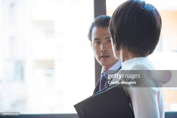 corporate japanese business man talks with executive black woman - atrium stock pictures, royalty-free photos & images