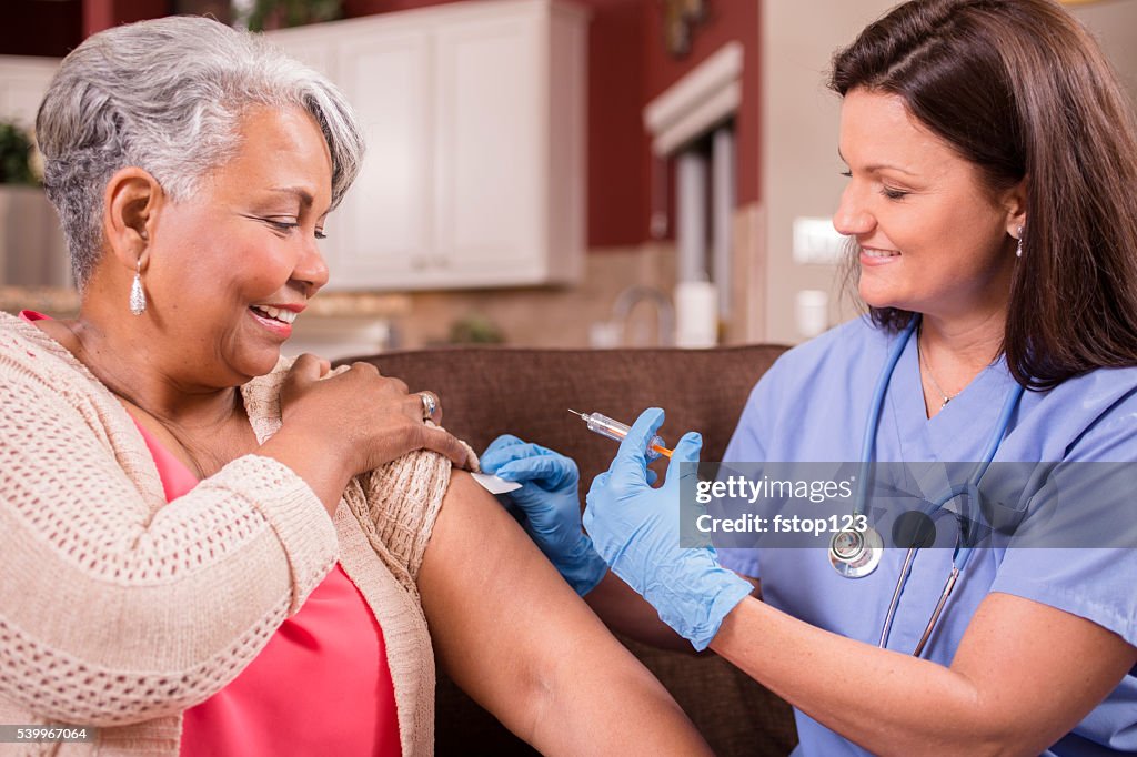 Home healthcare nurse giving injection to senior adult woman.