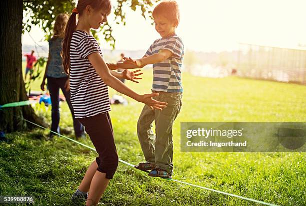 garoto tentando caminhada sobre slackline - corda bamba - fotografias e filmes do acervo