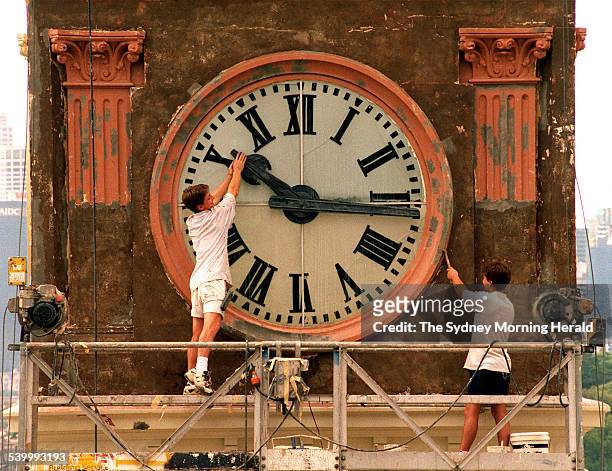 Painter Wayne Fleming of Minchenbury working on the Balmain Post Office Tower clock, playfully trys to stop time while co-worker, David Hamilton,...