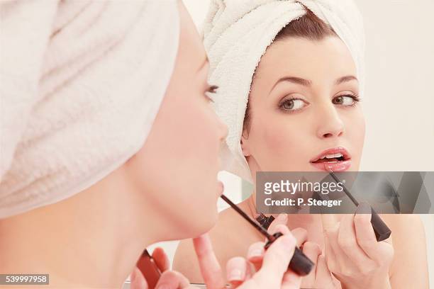 young woman applying lip gloss - shiny lips stock pictures, royalty-free photos & images