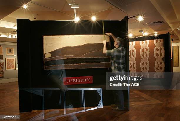 The finishing touches go into hanging 'Lundari ' by Rover Thomas in an exhibition of Aboriginal Art, which goes on display at Christie's auction...