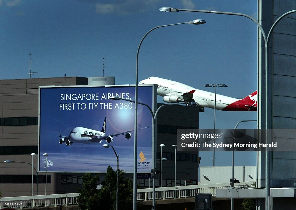 A Qantas plane takes off from Sydney Airport while a Singapore Airlines billboar