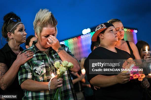 From left Kyra Murphy wife Crystal Murphy and Nicole Edwards and her wife Kellie Edwards observe a moment of silence during a vigil outside the Dr....