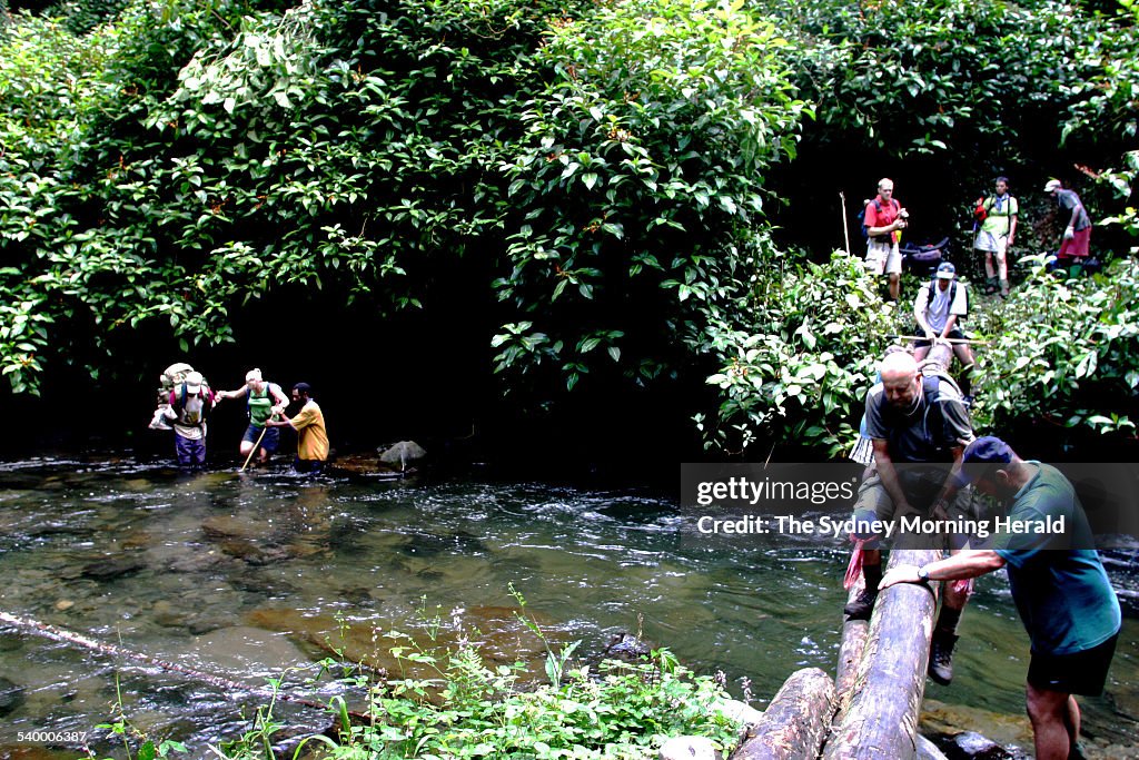 Trekkers cross a flowing creek after a steep decent from the village of Kagi, on
