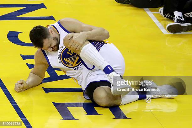 Andrew Bogut of the Golden State Warriors holds his knee in pain after sustaining an injury during the third quarter against the Cleveland Cavaliers...
