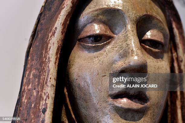 This picture taken on June 13, 2016 in Paris, shows a detail of a 17th century wooden virgin. A masterpiece of the Ottonian art , a golden cross with...