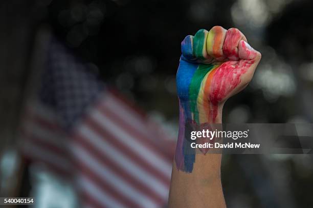 Defiant fist is raised near an American flag at a vigil for the worst mass shooing in United States history on June 13, 2016 in Los Angeles, United...