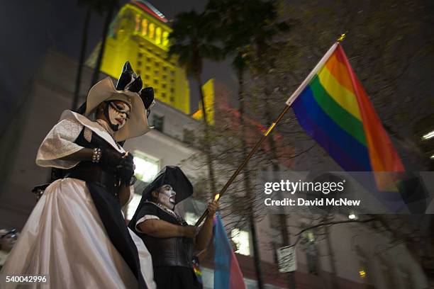 Members of the Sisters of Perpetual Indulgence lead people on a march around City Hall, which is lit in the colors of the rainbow flag to honor the...