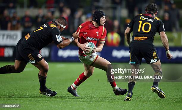Tom James of Wales is challenged by Waikato Chiefs players Siegfried Fisi'ihoi and Stephen Donald during the rugby union match between the Super...