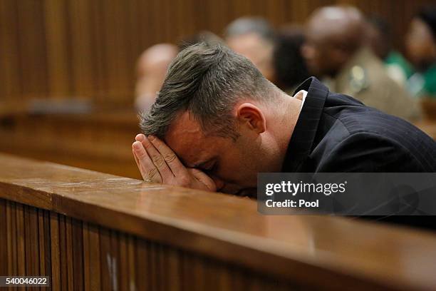 Oscar Pistorius puts his head in his hands as he sits inside the dock at the high court in Pretoria for his sentencing hearing at the high court in...