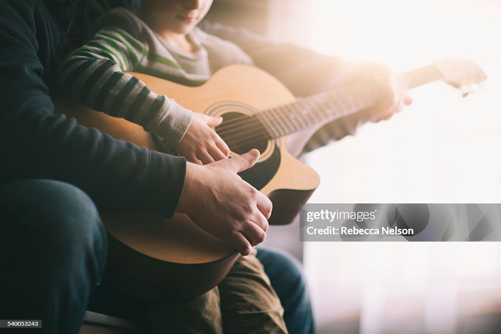 Father teaching his son to play guitar