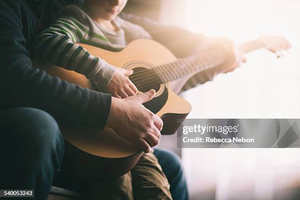 father teaching his son to play guitar - guitar imagens e fotografias de stock