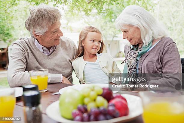 girl (6-7 years) at garden table with grandparents - 55 59 years stock-fotos und bilder